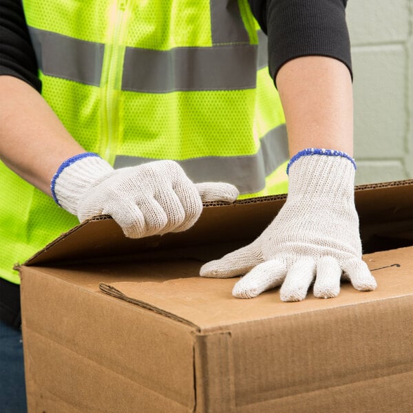 A person wearing Cordova polyester/cotton work gloves opening a box.