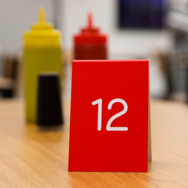 A red Cal-Mil table tent with white number twelve on it.