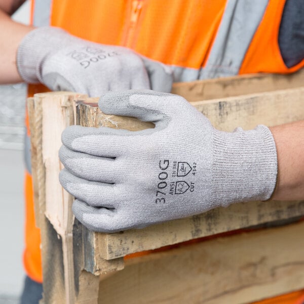 A person wearing Cordova grey HPPE gloves holding a piece of wood.