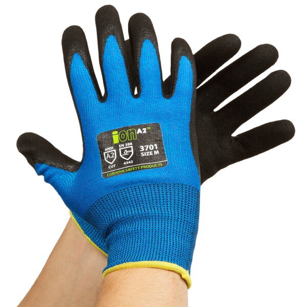 A pair of hands wearing blue and black Cordova iON gloves with black nitrile palms.