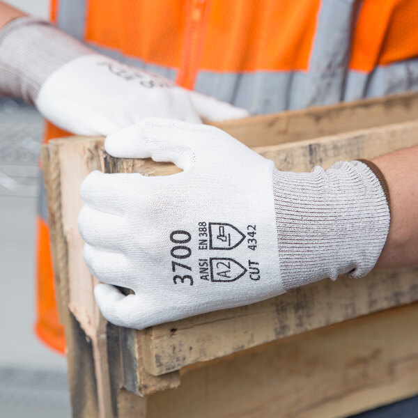 A person wearing Cordova white gloves with a white palm coating holding a wooden box.