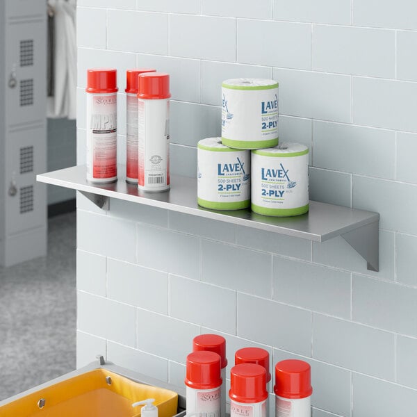 A Lavex stainless steel wall mount shelf with containers and cans on it.