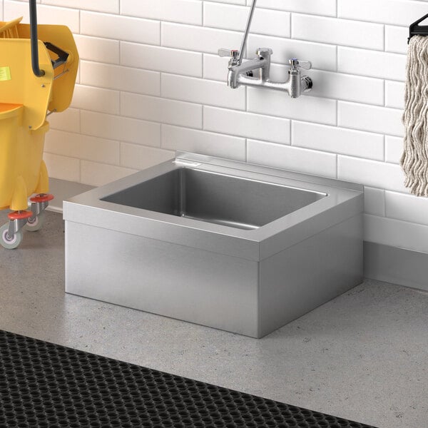 A Steelton stainless steel mop sink in a room with a mop and bucket.