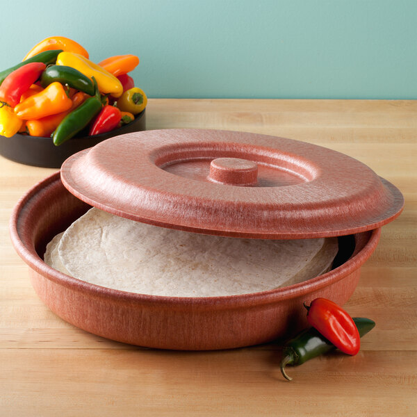 A red HS Inc. Tortilla Server with white tortillas inside on a table with peppers and other food.