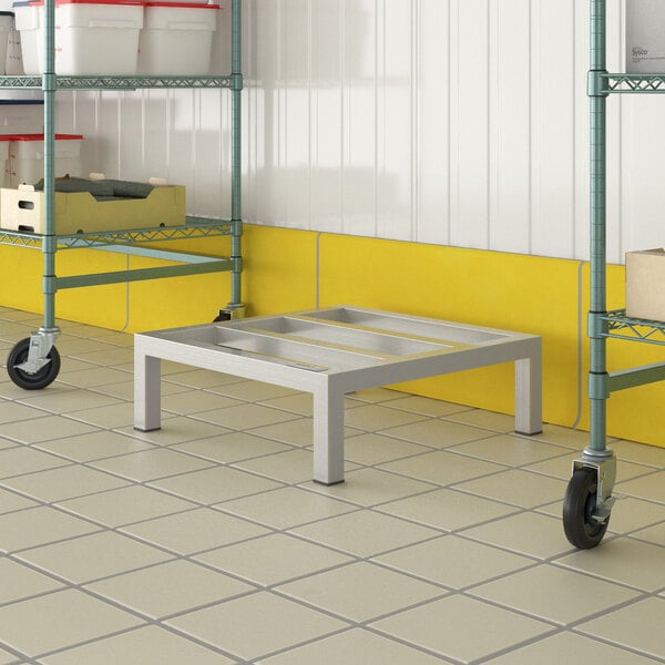 A Regency aluminum dunnage rack with wheels on a metal table.