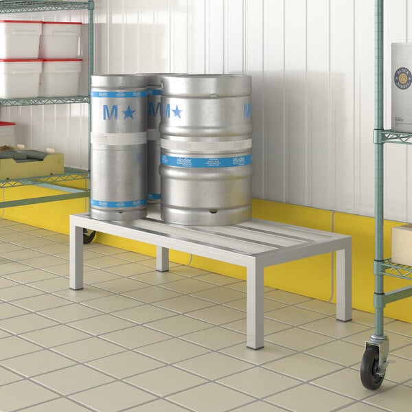 A white metal Regency dunnage rack with several beer kegs on it.