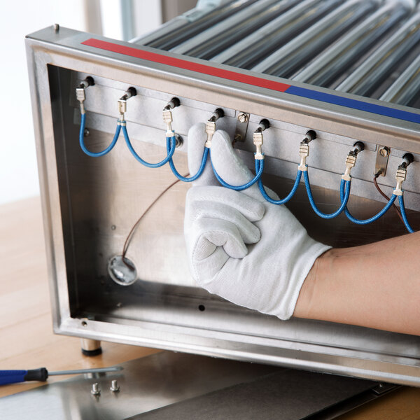 A person wearing Cordova white inspection gloves working on a machine.