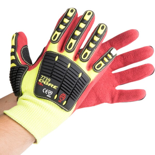 A close-up of a hand wearing a yellow and red Cordova OGRE-CR+ cut-resistant glove with red palm coating.