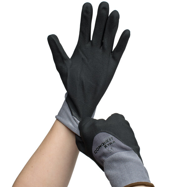 A person putting on gray Cordova Conquest gloves with black and gray palms.