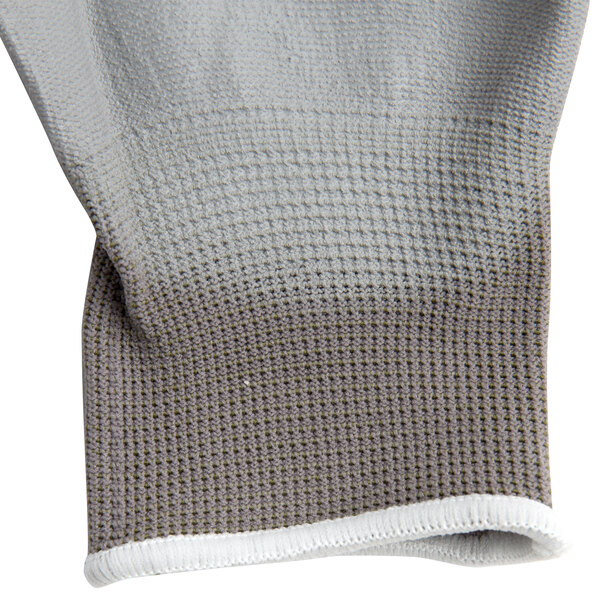 A close up of a gray and white nylon glove with gray palm coating.