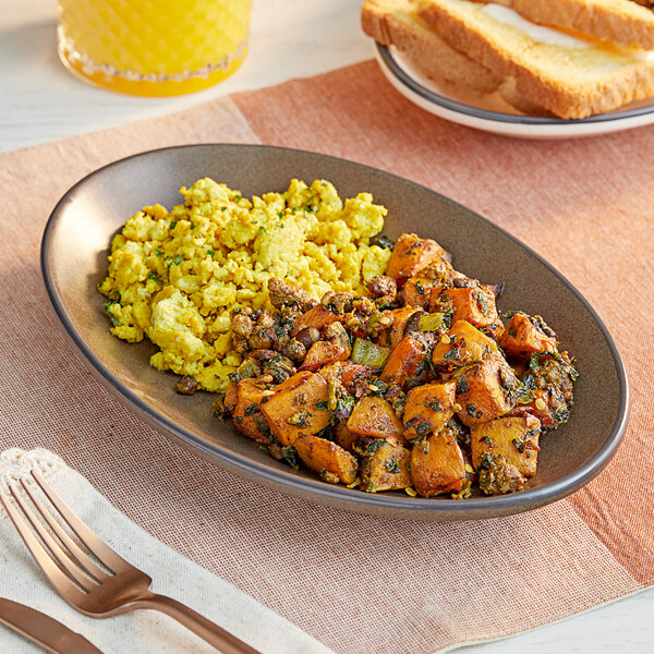 A plate of Stone's Throw Foods Chorizo Skillet on a place mat with a fork and a glass of orange juice.