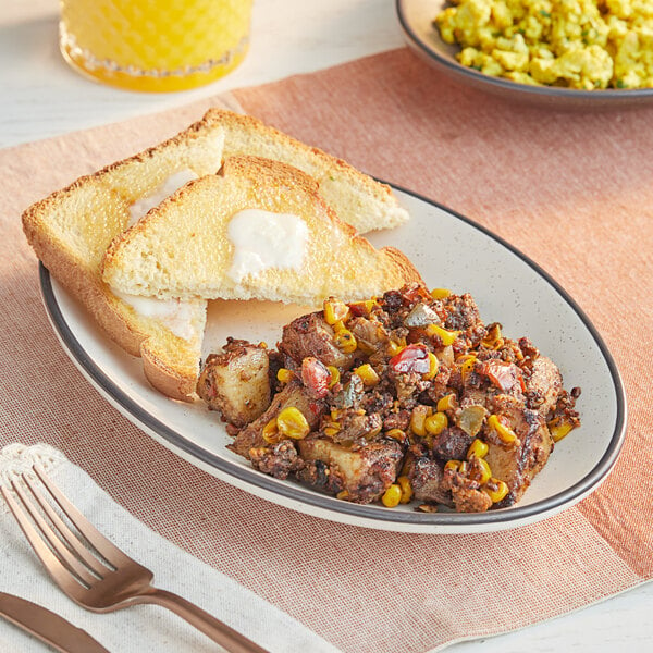 A plate of Stone's Throw Foods Vegan Chickpea Chorizo Fiesta Skillet with a fork and knife on a white napkin.