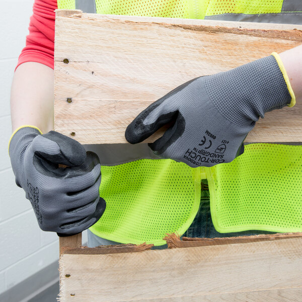 A person wearing Cordova Cor-Touch grip gloves holding a piece of wood.