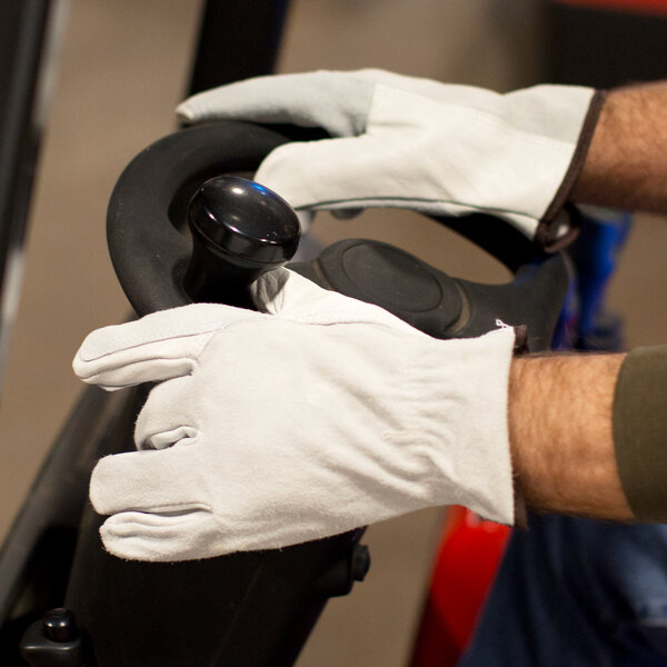 A person wearing Cordova leather gloves while holding a black steering wheel.