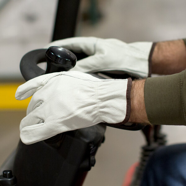 A person wearing Cordova Premium grain cowhide leather driver's gloves while driving a vehicle.