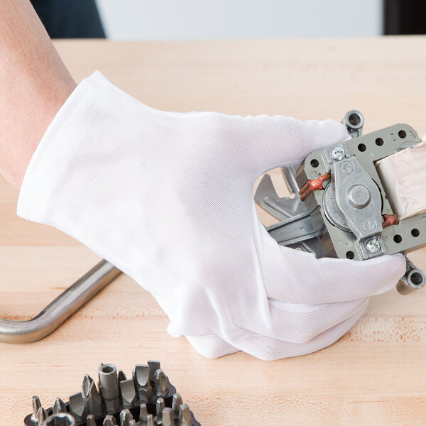 A hand in a white Cordova glove holding a metal object.