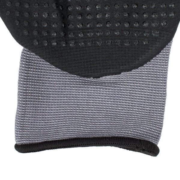 A close up of a small Cordova Conquest Max black and grey warehouse glove with nitrile dots and hand coating.