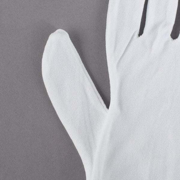A Cordova white nylon inspection glove on a gray surface.