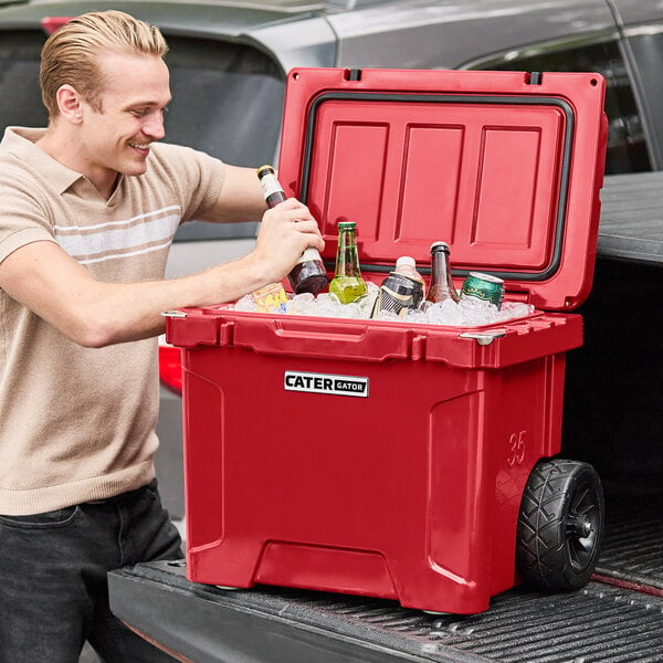 A man opening a CaterGator red cooler full of bottles and ice.