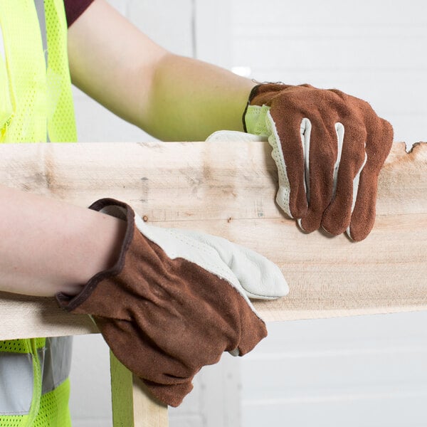 A person wearing Cordova Select Grain Cowhide Leather Driver's Gloves holding a piece of wood.