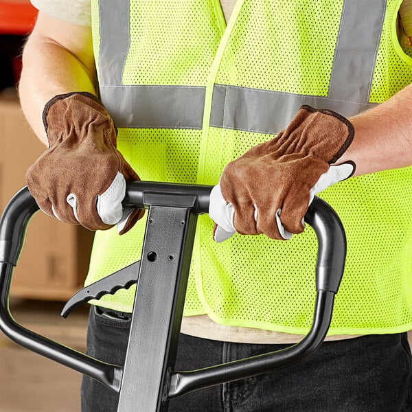 A person wearing Cordova grain and split leather driver's gloves using a hand truck.