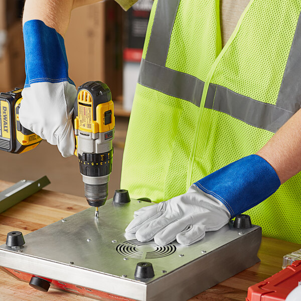 A person wearing Cordova premium goatskin welder's gloves using a drill to make a hole in metal.