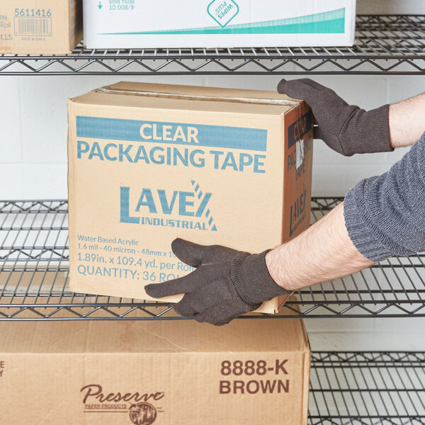 A person holding a box of Cordova Standard Brown Polyester / Cotton Jersey Gloves.