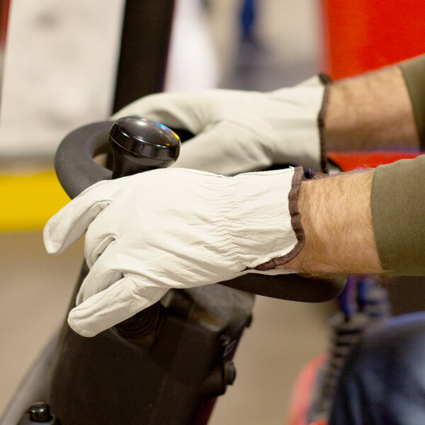 A person wearing Cordova Standard Grain Cowhide driver's gloves while driving a vehicle.