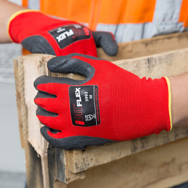 A person wearing a Cordova iON Flex Hi-Vis red nylon glove with dark gray crinkle latex palm coating.