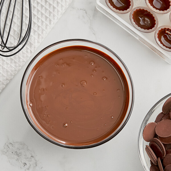 A bowl of liquid chocolate next to a bowl of Republica del Cacao Mexico Dark Chocolate chips.