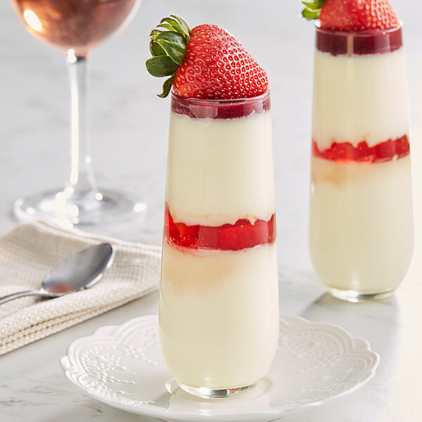 A couple of desserts in glasses with strawberries on a white cloth.