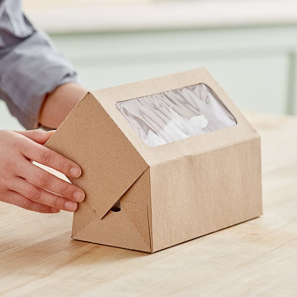 A person holding a Baker's Mark Kraft bakery box with a plastic window.