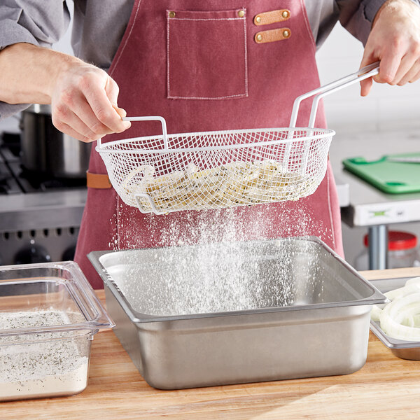 A person pouring flour into a silver metal mesh breading basket.