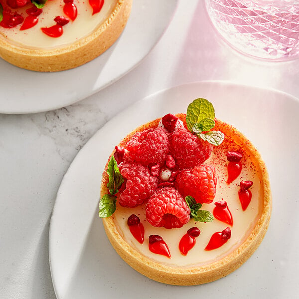 A dessert with raspberries and mint leaves on a white plate.