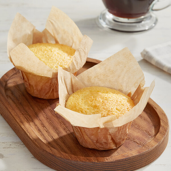 Two Baker's Mark unbleached natural kraft muffins on a wooden tray.