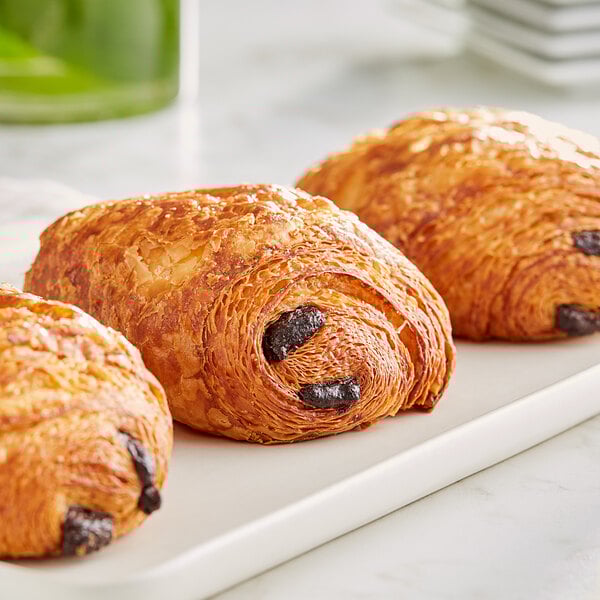 Valrhona dark chocolate batons on a white plate with croissants.