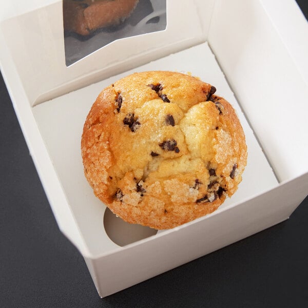 A chocolate chip muffin in a white Baker's Mark cupcake and muffin insert in a white box.