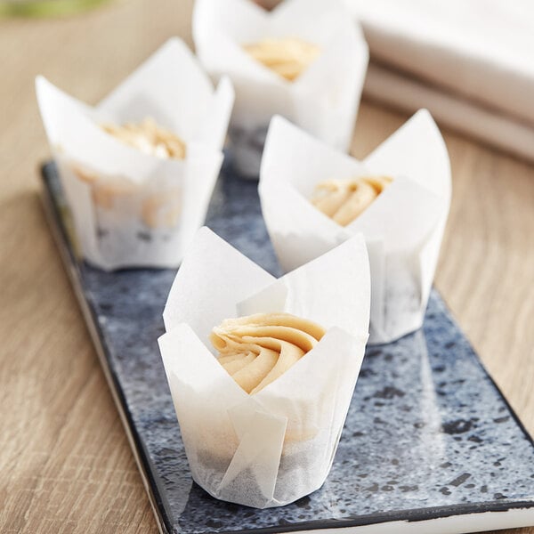 Three Baker's Mark white tulip mini cupcakes with peanut butter on a plate.