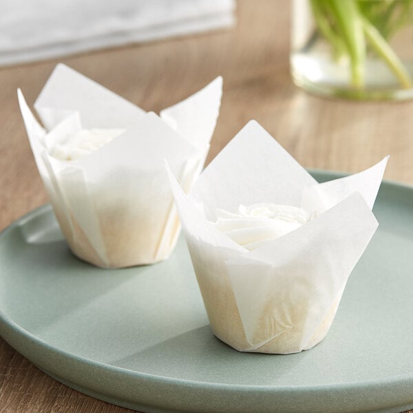 Two cupcakes in Baker's Mark white tulip baking cup wrappers on a plate.