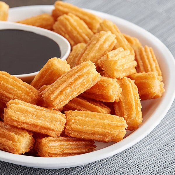 A plate of Hola Churros 2" Churro Bites with chocolate sauce.