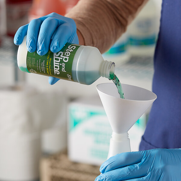 A person in blue gloves pouring green liquid into a funnel.