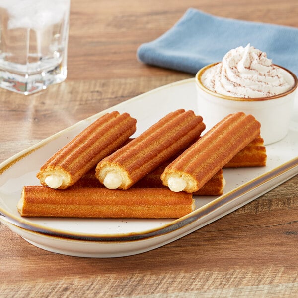 Bavarian cream filled mini churros on a plate with whipped cream and water.