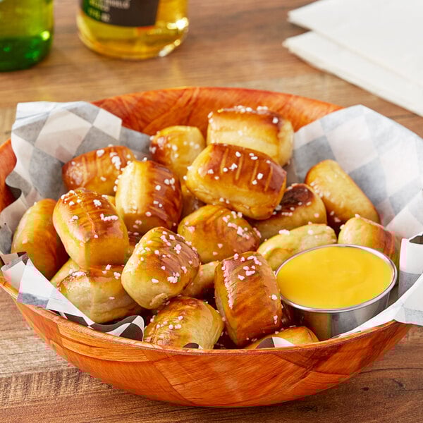 A bowl of J & J Snack Foods SuperPretzel Bavarian Soft Pretzel Bites with mustard and cheese sauce.