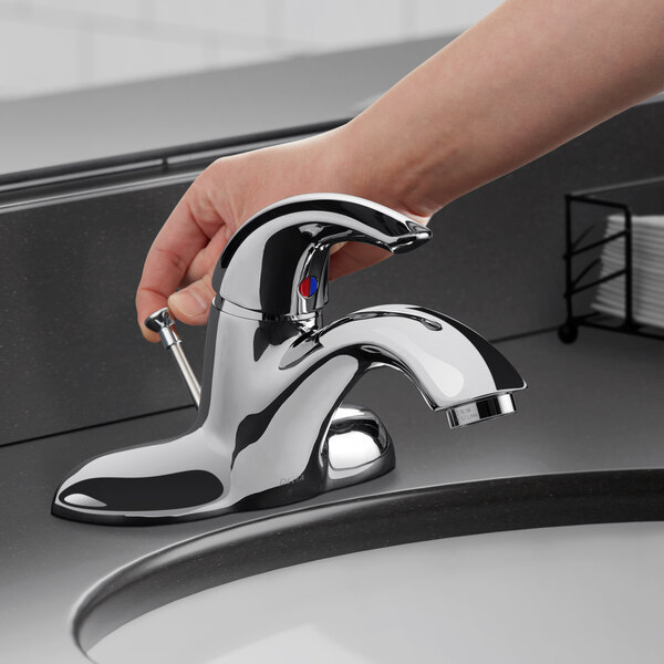 A hand opening a Delta single lever deck-mount lavatory faucet over a sink.