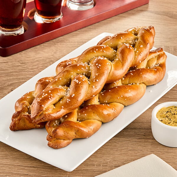 A plate with SuperPretzel Soft Pretzel Braids on a table in a stadium concession stand.