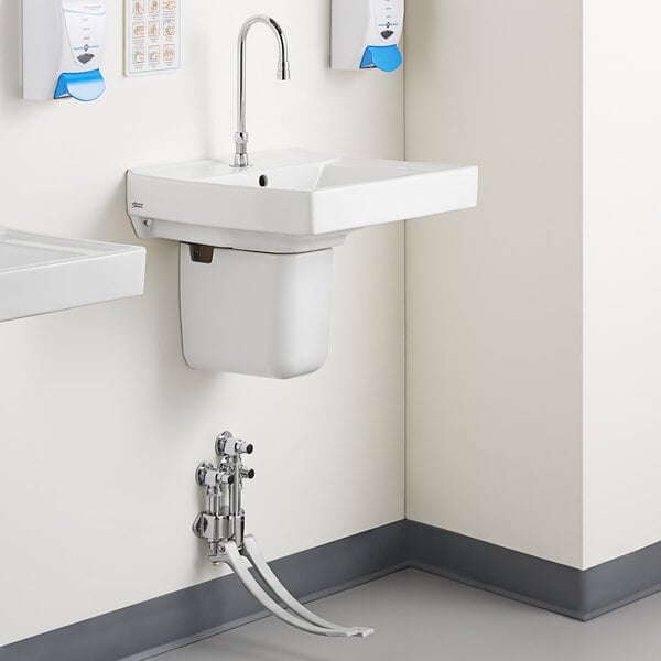 A white bathroom sink with a Delta foot-operated faucet.