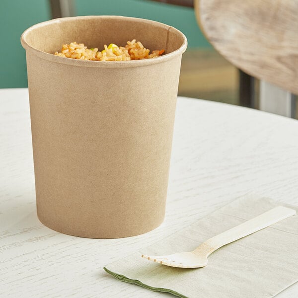 A brown Choice paper food cup filled with rice on a table with a wooden fork.