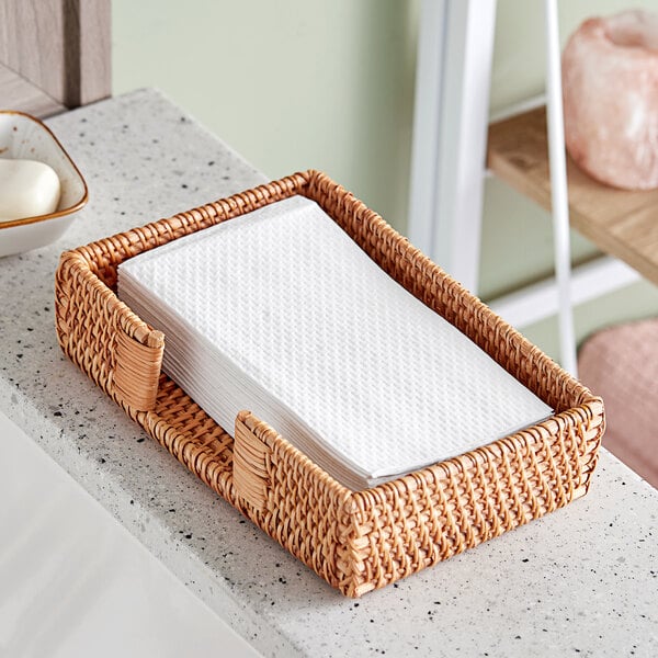 A wicker basket on a kitchen counter filled with Earthwise white guest towels.