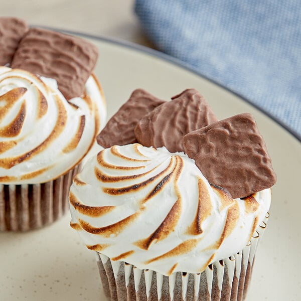 Milk chocolate covered mini graham crackers in a close up dessert with white frosting and chocolate squares.