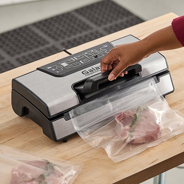 A person using a Galaxy vacuum sealer to package meat.